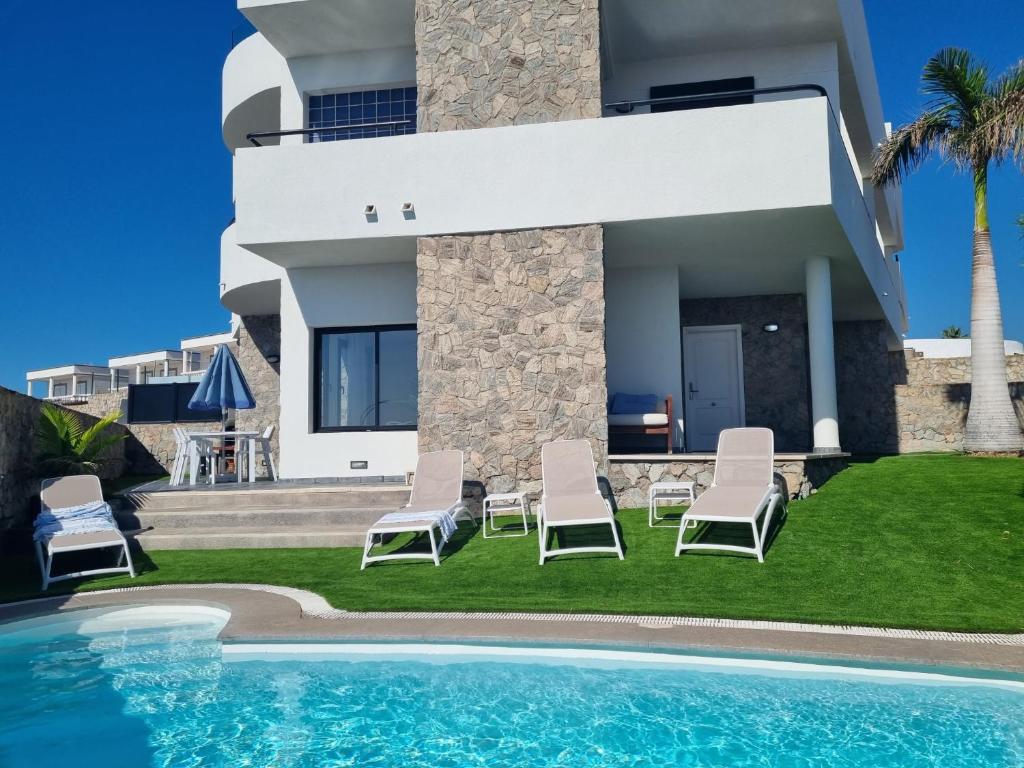 a villa with a swimming pool in front of a house at Villa The Views in Puerto Rico de Gran Canaria