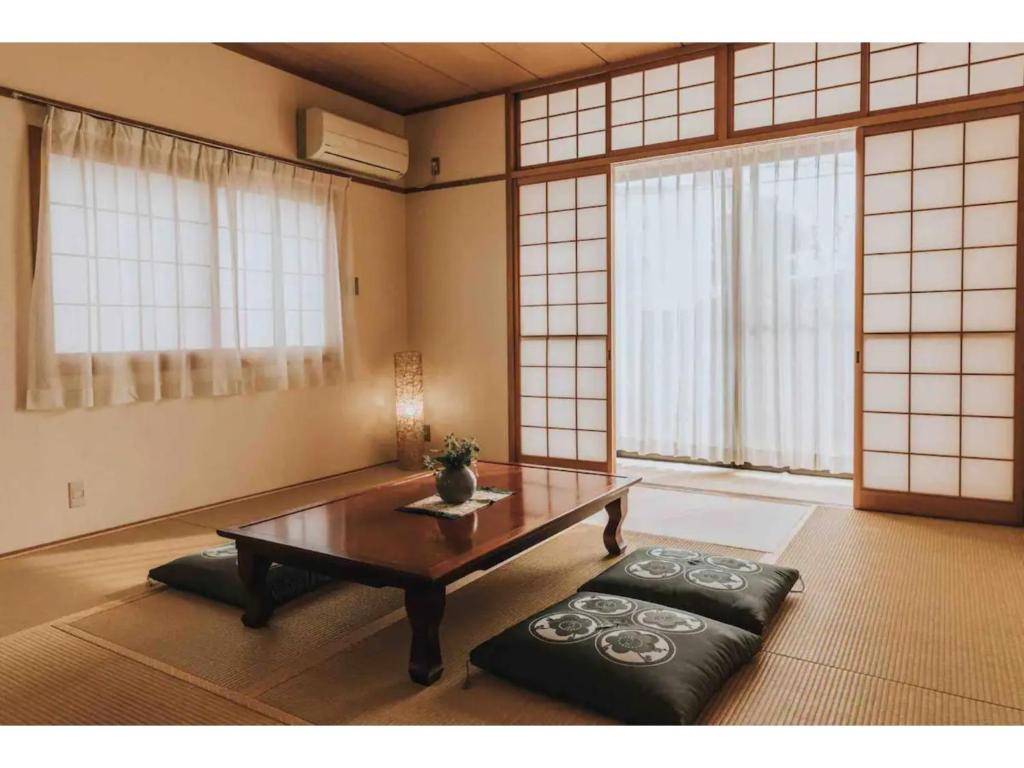 ein Wohnzimmer mit einem Couchtisch und großen Fenstern in der Unterkunft MEILAN HOUSE - Vacation STAY 13804 in Osaka