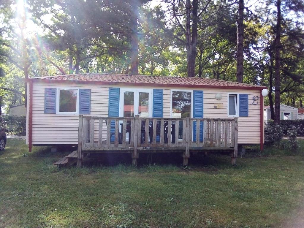 una casa pequeña con porche y terraza en Mobil-home 6 personnes 3 chambres, en La Boissière-de-Montaigu