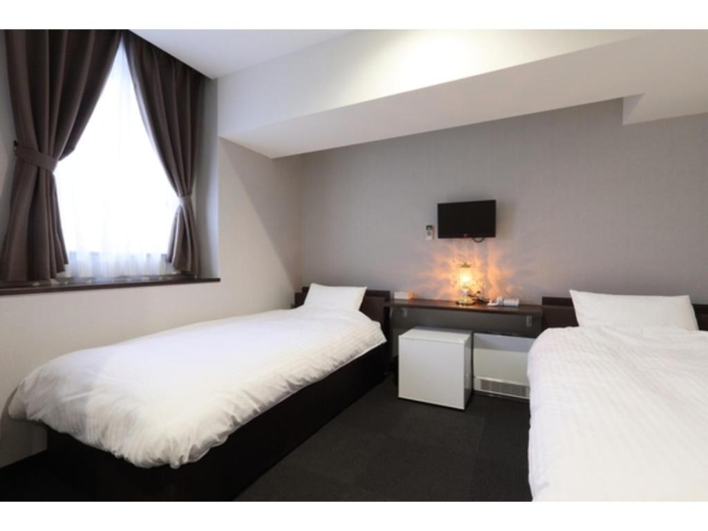 a room with two beds and a desk with a tv at Kusatsu Onsen 326 Yamanoyu Hotel - Vacation STAY 10472v in Kusatsu