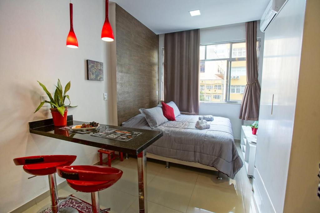 1 dormitorio con cama, mesa y taburetes rojos en Estudio confortável em Copacabana - NSC405 Z4, en Río de Janeiro