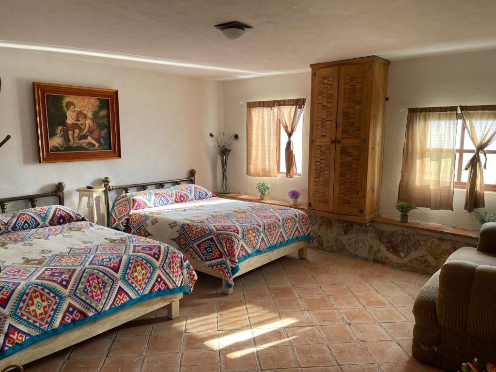 1 Schlafzimmer mit 2 Betten, einem Sofa und Fenstern in der Unterkunft Jardín Quinta Las Fuentes Cabañas, Valsequillo. PUEBLA in Puebla