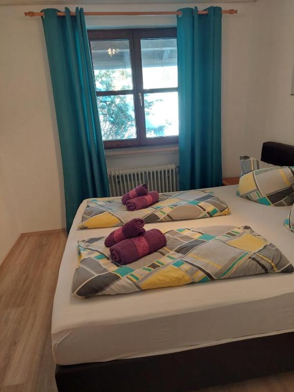 two beds in a bedroom with blue curtains at Ferienwohnung am Walchensee in Walchensee