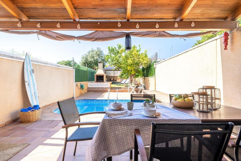 un patio con mesa, sillas y piscina en Another day in Paradise, en Calafell