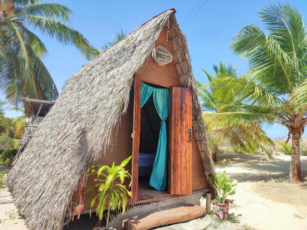 eine kleine Hütte am Strand mit Palmen in der Unterkunft Ecocamping Lumiar in Amontada