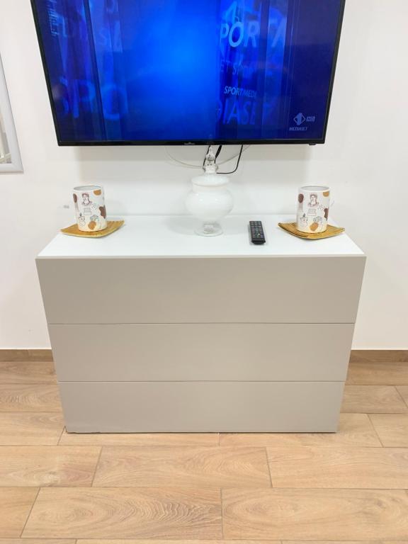 een tv op de top van een witte dressoir met twee koffiekopjes bij b&b la corte in centro in Caserta