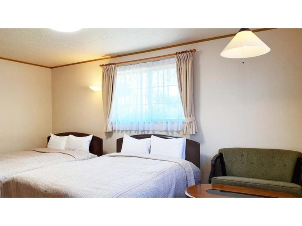 Habitación con 2 camas, silla y ventana en Sudomari no Yado Sunmore - Vacation STAY 46722v, en Nikko