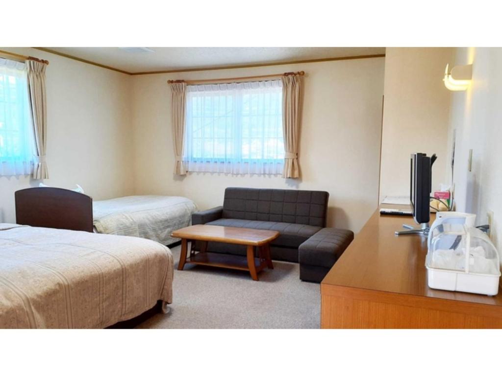 Cette chambre comprend un lit, un canapé et une télévision. dans l'établissement Sudomari no Yado Sunmore - Vacation STAY 46732v, à Nikkō