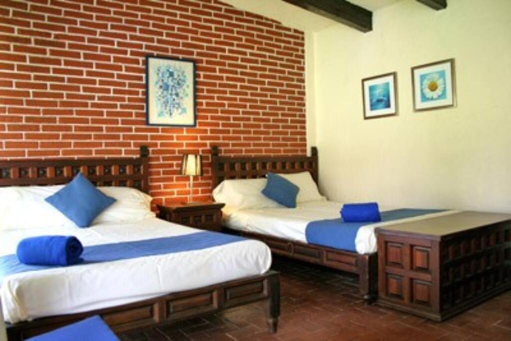 twee bedden in een kamer met een bakstenen muur bij Villa Esperanza in Ticumán