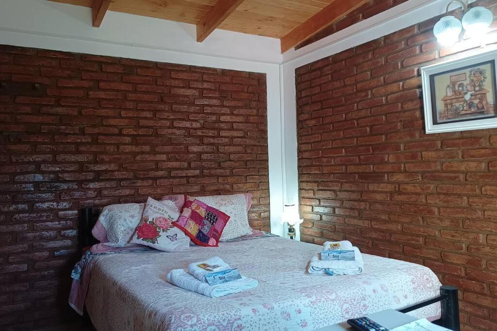 1 dormitorio con 1 cama en una pared de ladrillo en estudio CL, monoambiente confortable en El Calafate