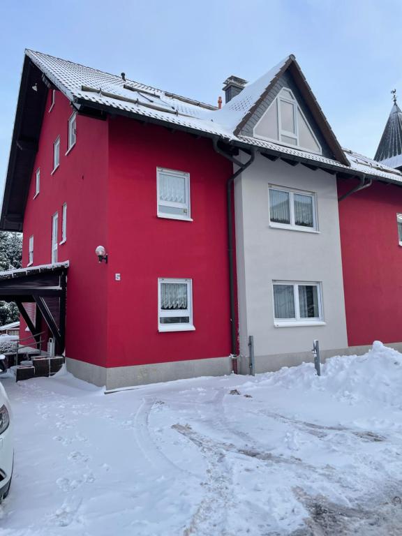 a red and white house with snow on the ground at Visit_Oberhof in Oberhof