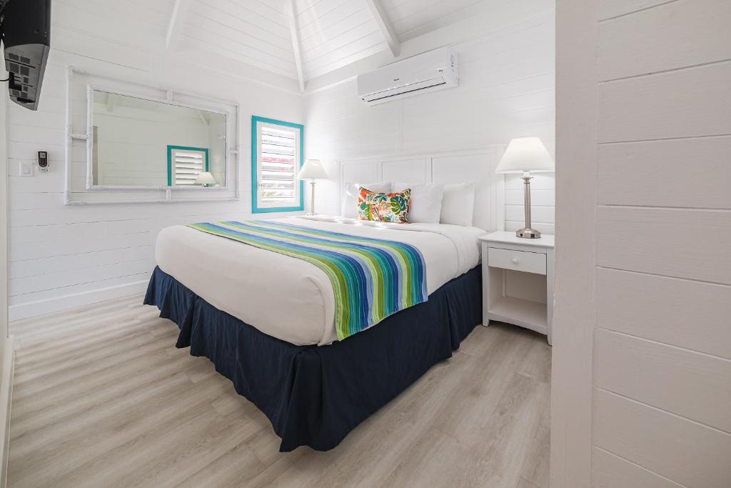 a white bedroom with a bed and a desk at La Vista Resort in Simpson Bay