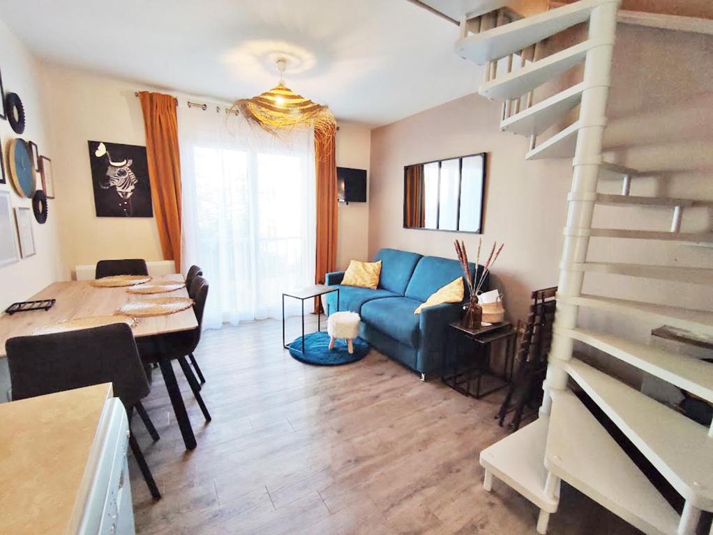 een woonkamer met een blauwe bank en een tafel bij L'Escampette, Duplex T3, centre Luchon, wifi, casier à skis, 4 personnes in Luchon