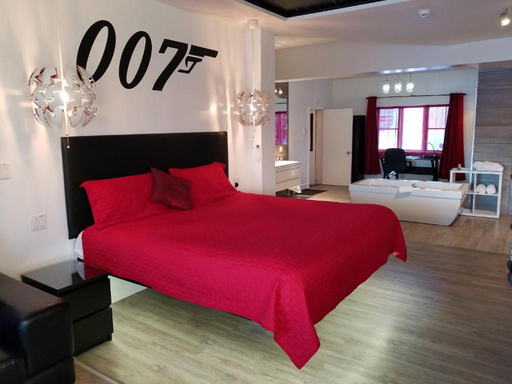 a bedroom with a red bed and a living room at Auberge Aux Nuits de Rêve in Sainte-Agathe-des-Monts