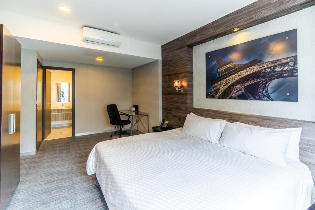 a hotel room with a white bed and a painting on the wall at Elite 47 Interlomas in Mexico City