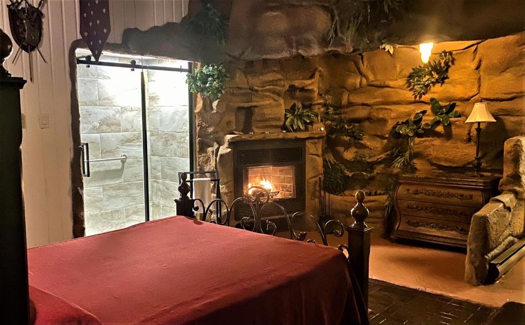 a stone room with a fireplace and a table and a bed at Auberge Aux Nuits de Rêve in Sainte-Agathe-des-Monts