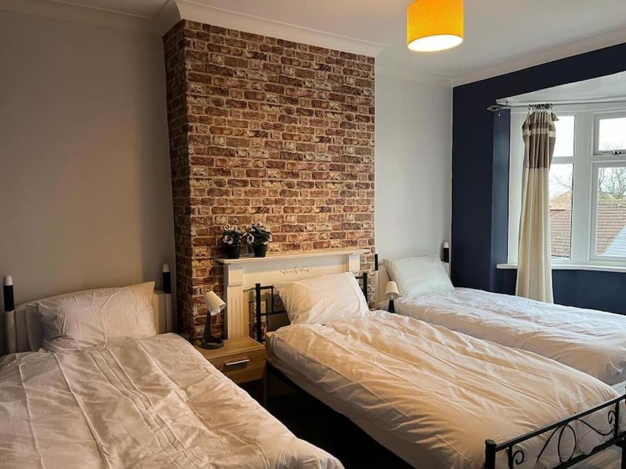 1 dormitorio con 2 camas y pared de ladrillo en Ovington Grove 2 fully equipped kitchen free parking 3 bedrooms Netflix en Newcastle