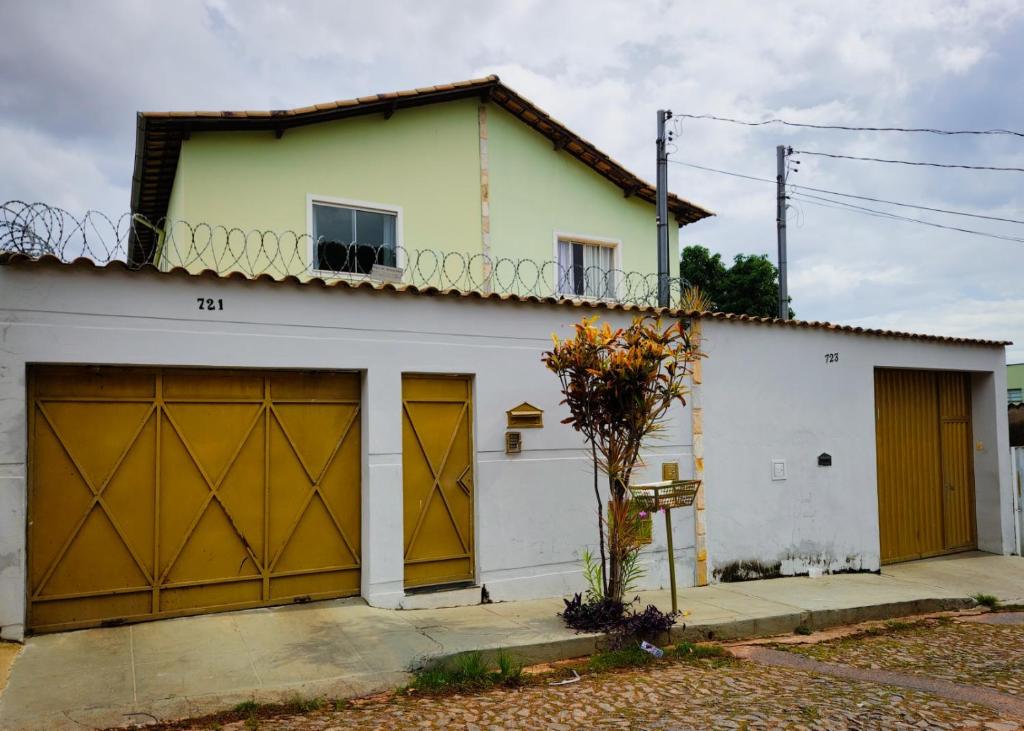 a white house with a garage with yellow doors at Trem bão de dormir hostel in Belo Horizonte
