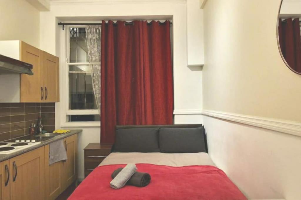 a kitchen with a red curtain and a bed in a room at Private London Kensington studio 2 mins from tube in London