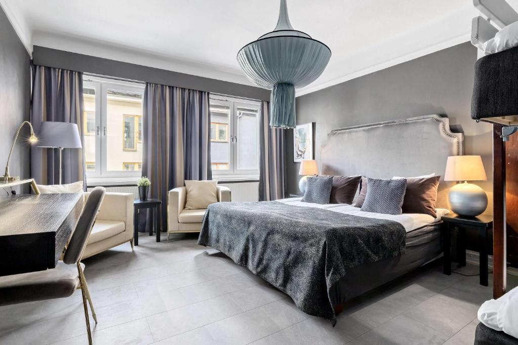 een slaapkamer met een bed, een stoel en een tafel bij Centric Hotel in Norrköping