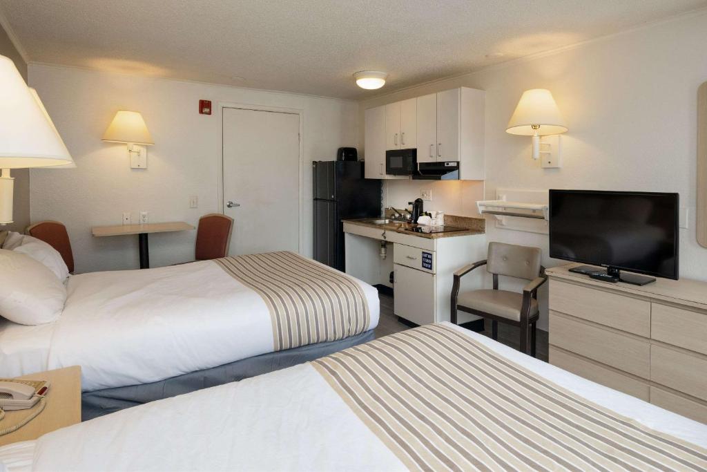 a hotel room with two beds and a flat screen tv at Suburban Studios Mentor - Cleveland Northeast in Mentor