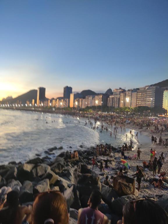 una multitud de personas en una playa al atardecer en Apto Mariza Copacabana, en Río de Janeiro