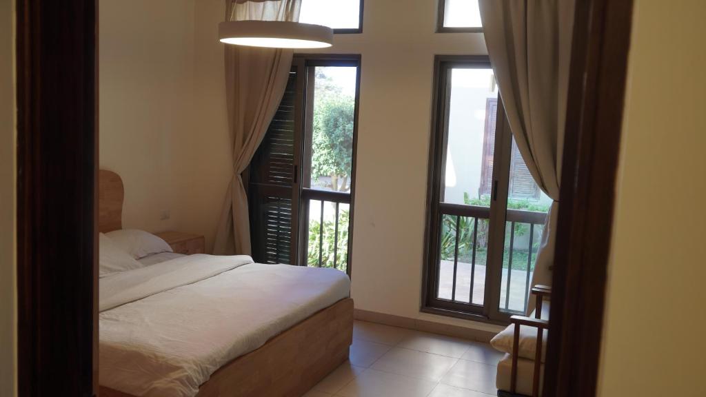 a bedroom with a bed and two large windows at Ground floor apartment by circular pool in Talabay (sweet coffee apartment) in Aqaba