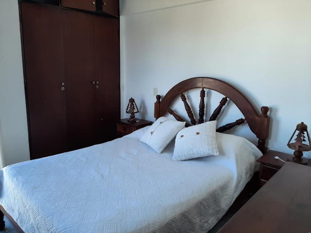 1 dormitorio con 1 cama grande con sábanas y almohadas blancas en Departamento 2 ambientes frente al mar con cochera en Mar del Plata