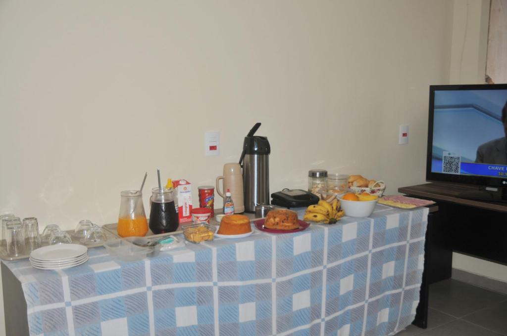 una mesa con comida encima y TV en Hotel hawaii, en Campos dos Goytacazes