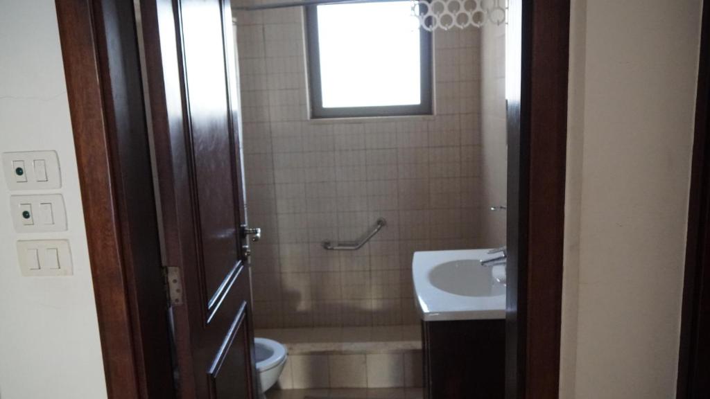 baño con lavabo y aseo y ventana en Romantic chalet between swimming pools and close to the seashore, en Áqaba