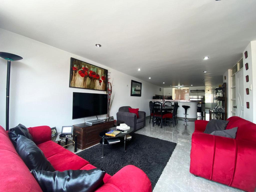 sala de estar con sofá rojo y TV en Ayli Apart Hotel, en Arequipa