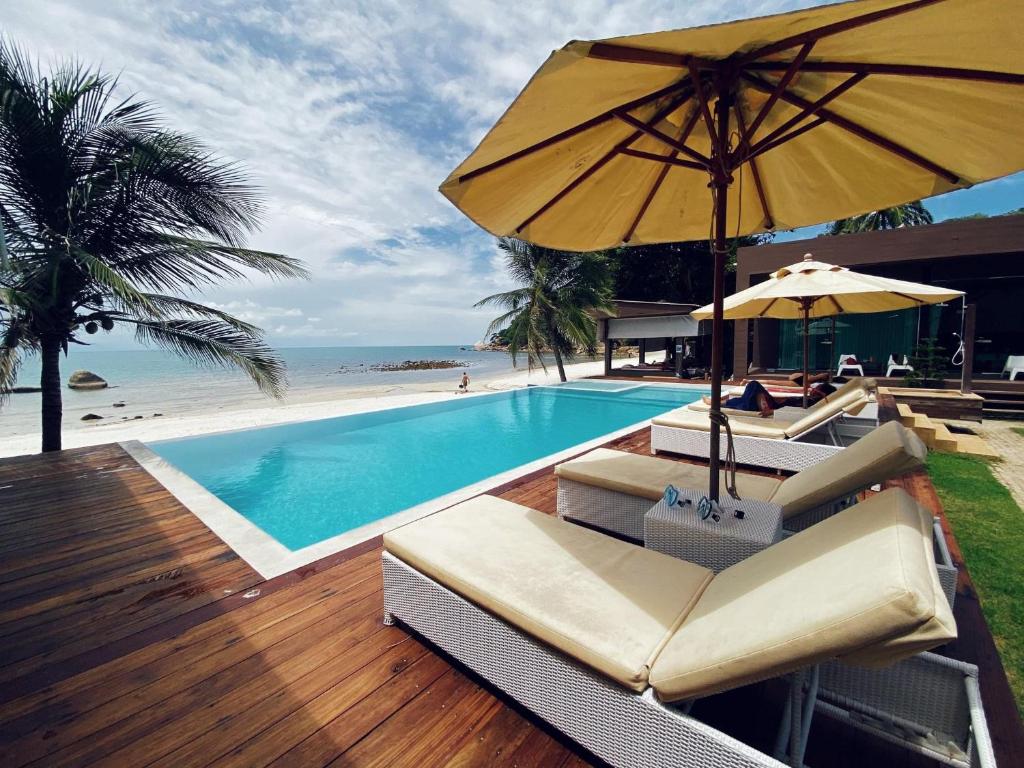 een zwembad met stoelen en een parasol naast het strand bij Silver Beach Resort in Lamai