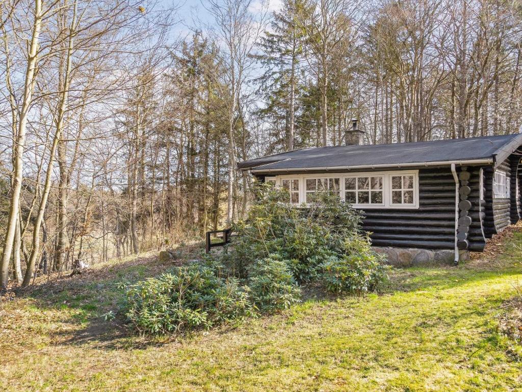 una cabina nel bosco con una panchina davanti di 4 person holiday home in Frederiksværk-By Traum a Frederiksværk
