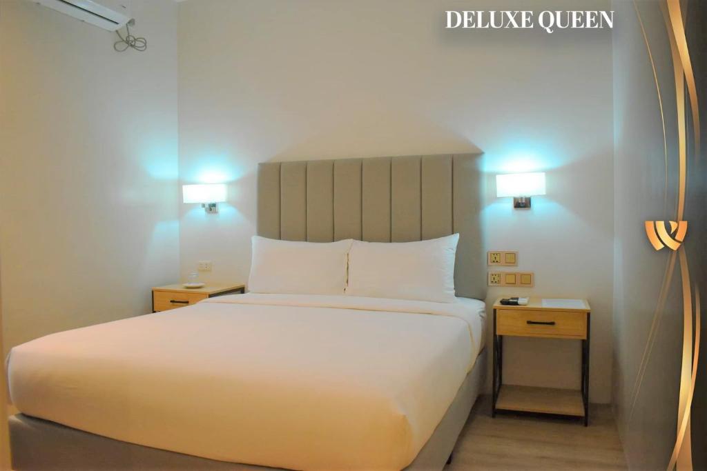 a bedroom with a white bed and two night stands at West Prime Hotel in Calbayog
