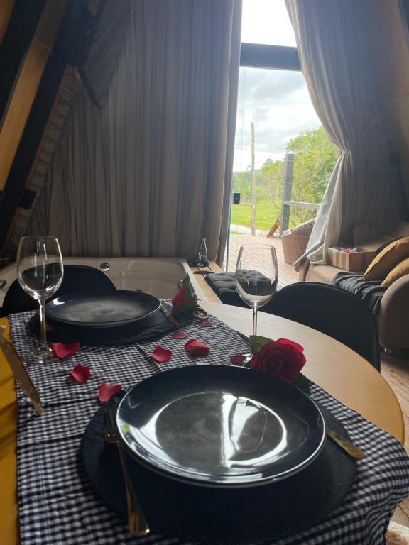 una mesa con dos platos y copas de vino. en Chalé Aconchegante - TEMOS O CHALÉ BRANCO DISPONÍVEL NESTE FINAL DE SEMANA, en Camboriú