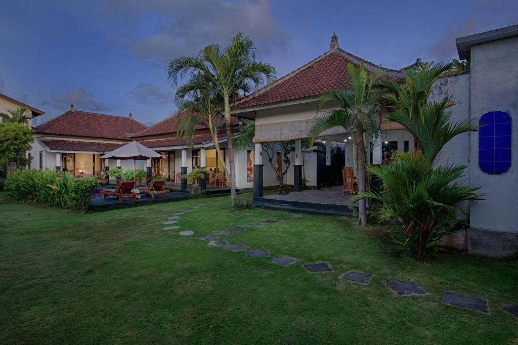 坎古的住宿－My Villa and Resort Canggu，一个带椅子和棕榈树的庭院的房子