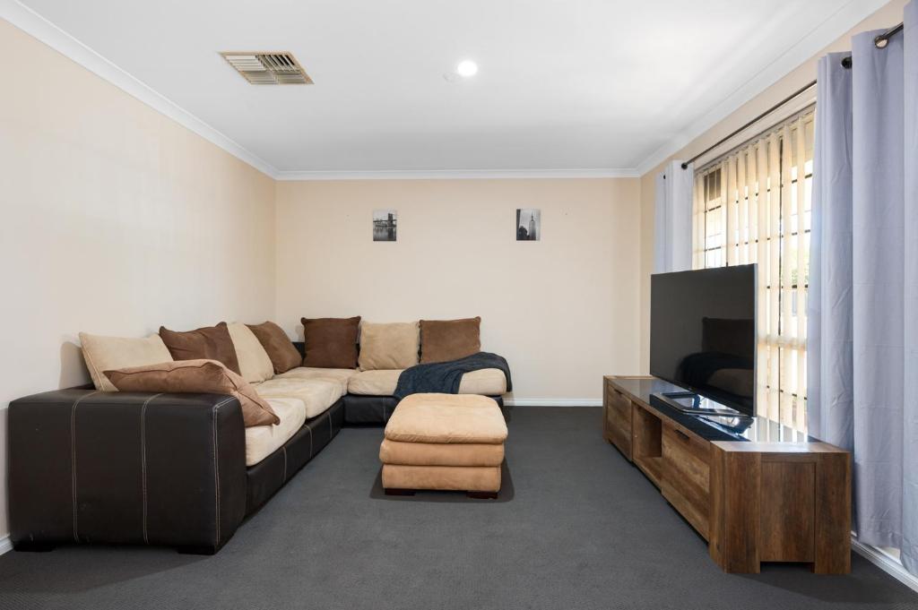 sala de estar con sofá y TV en Bea-Vic Home. Your home away from home., en Kalgoorlie