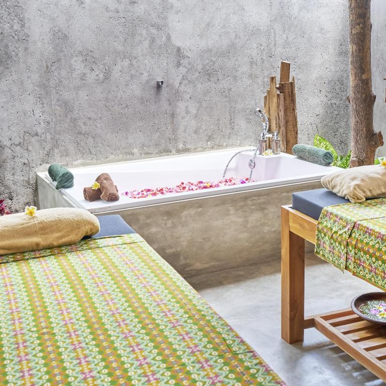 a bathroom with a bath tub and a bed at Anda Amed Villas & Spa in Amed