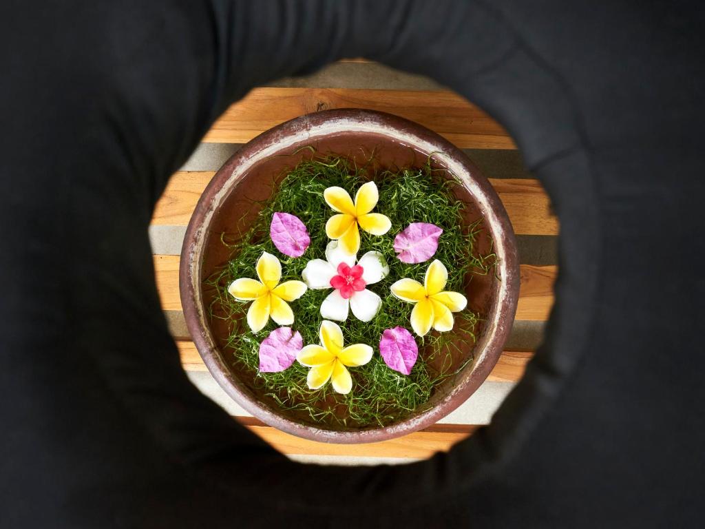 a bowl filled with flowers on top of a table at Anda Amed Villas & Spa in Amed