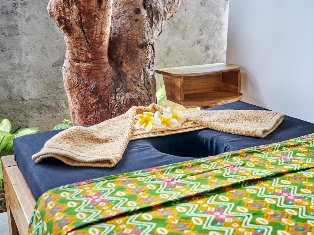 a bed with towels and a tree in the background at Anda Amed Villas & Spa in Amed
