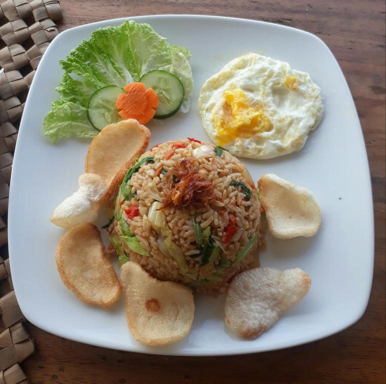a plate of food with a sandwich and eggs and bread at Anda Amed Villas & Spa in Amed