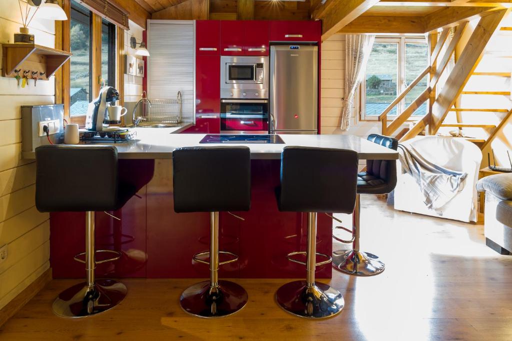 a kitchen with red cabinets and a counter with bar stools at AndBnB I Duplex Rustico en Plena Naturaleza I Parking Gratis in Canillo