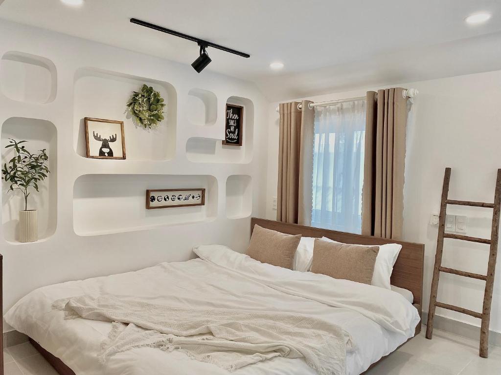 a white bedroom with a bed and a ladder at Mưa home in Da Nang