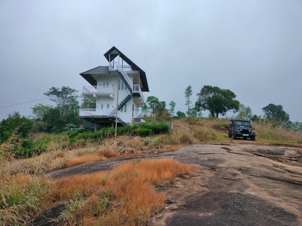 a house on the side of a hill with a truck at Anemoi Chimes Resort Calvarymount in Idukki