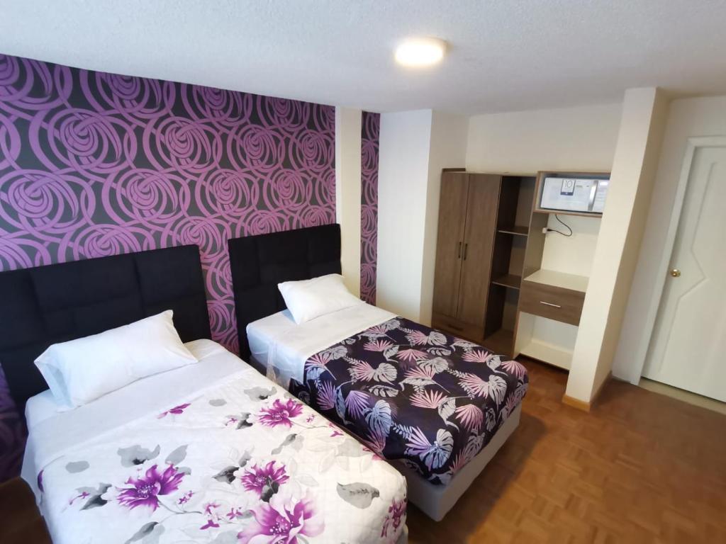 een slaapkamer met 2 bedden en een paarse muur bij Habitación doble Independiente frente al parque la Carolina in Quito
