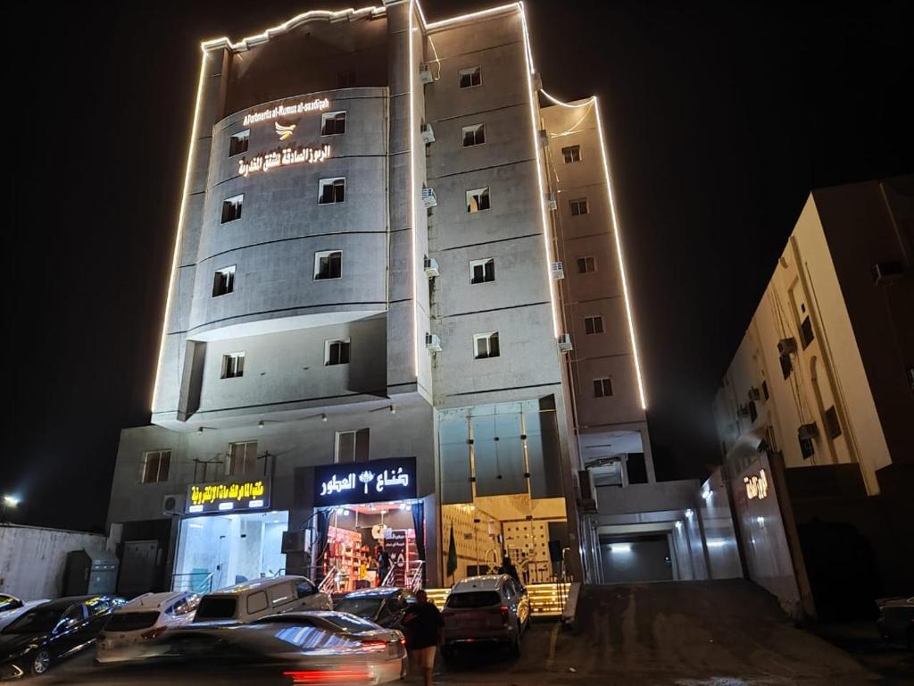 a tall building with cars parked in front of it at الرموز الصادقة للشقق المخدومة Apartments alrumuz alsadiqah in Jeddah