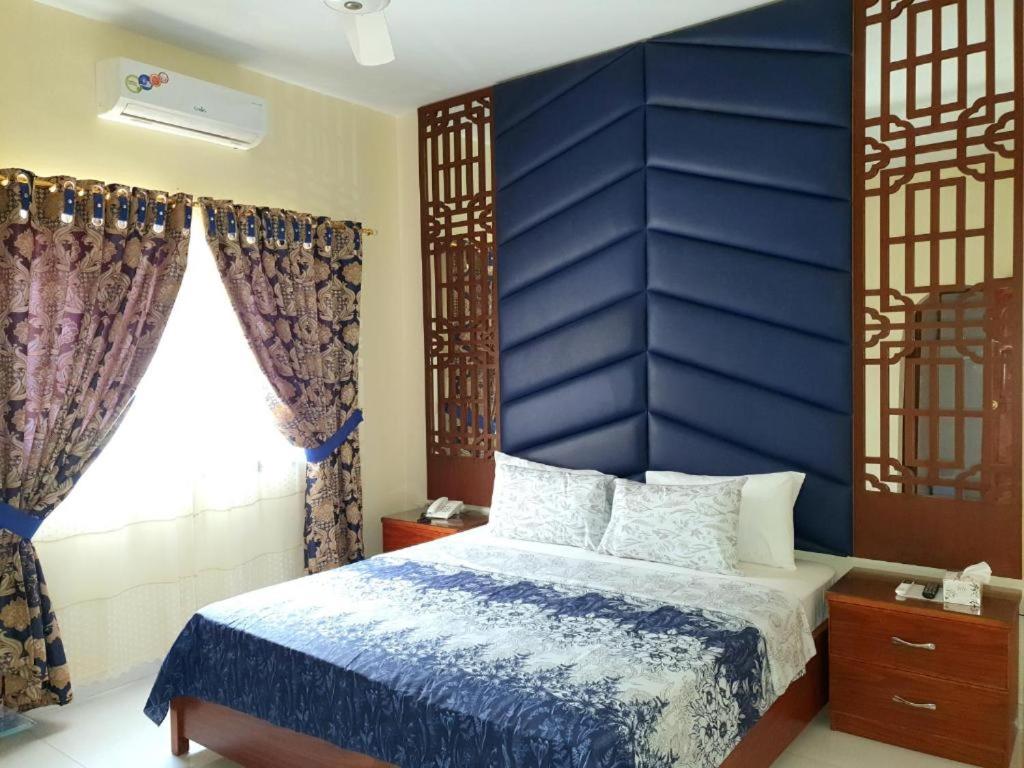 a bedroom with a blue headboard and a bed at Hotel Imperial Karachi in Karachi