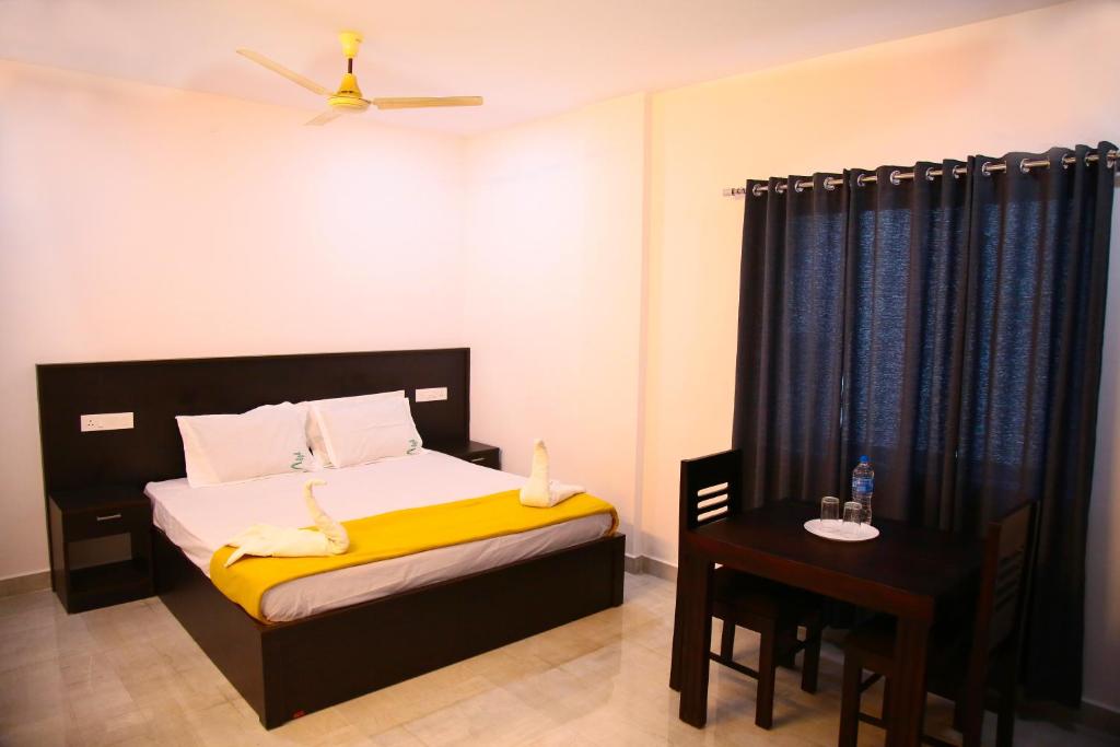 a bedroom with a bed with a yellow blanket and a table at Thekkady Travel Rooms in Thekkady
