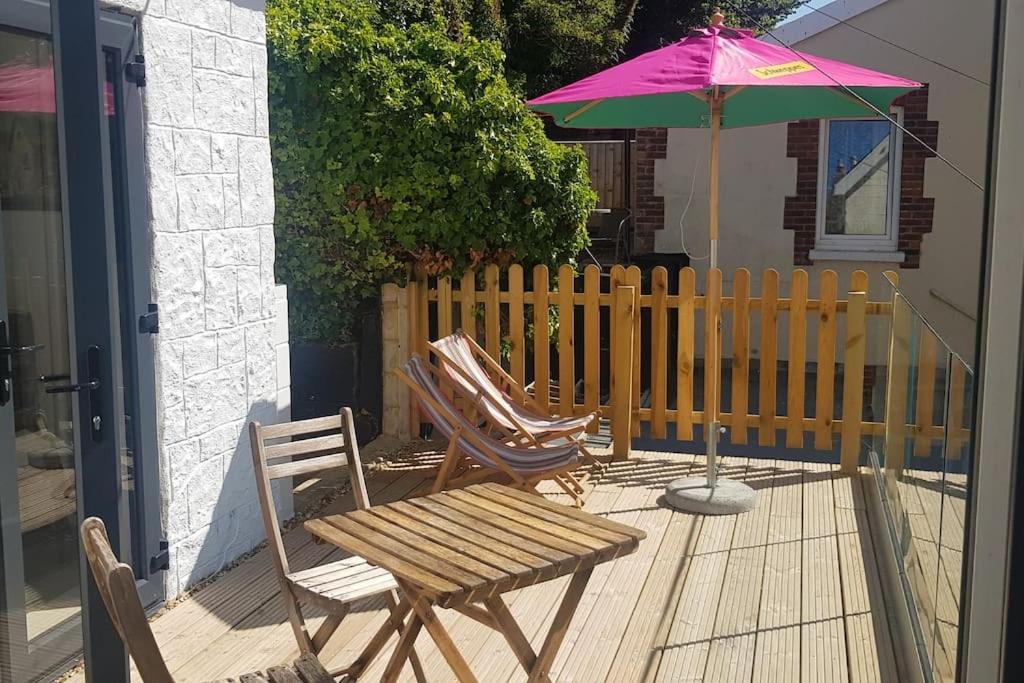 two chairs and a table and an umbrella on a deck at Wheelers Bay Apartment in Ventnor