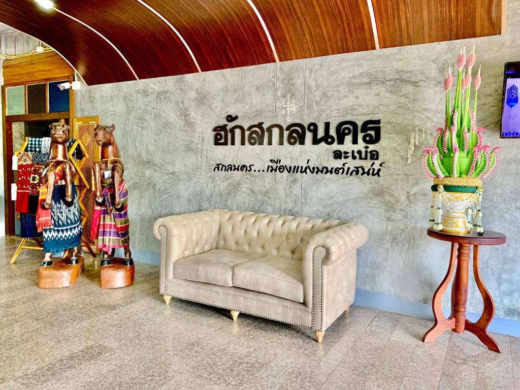 a living room with a couch in front of a wall at Hug Sakhonnakhon Hotel in Sakon Nakhon